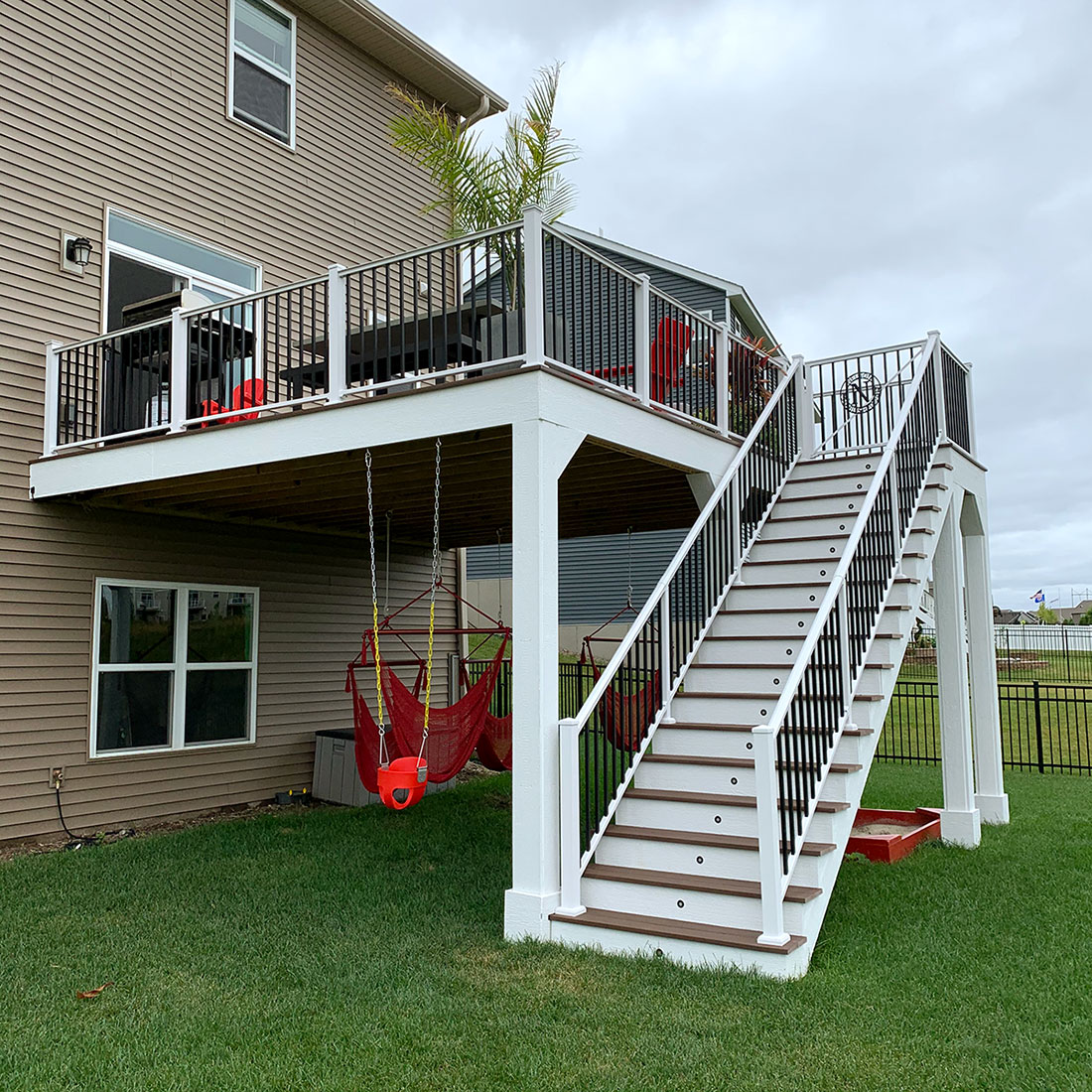 Outdoor deck with a staircase, featuring red chairs and a table, built by Carter Custom Construction