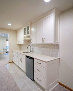 Custom-Basement-Home-Bar_Twin-Cities_MN Basement home bar remodeling project with white cabinets, a dishwasher and sink, and white and light gray hexagon tile backsplash, remodeled by Carter Custom Construction