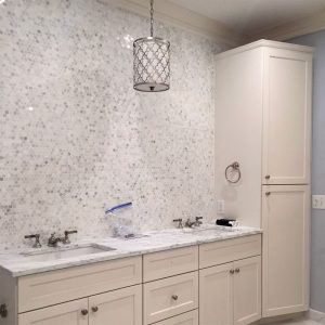 Custom-Bathroom-Remodeling-Vanity-Tile_Twin-Cities_MN Bathroom remodel with a wall of small octagon white and gray tiles around the vanity, white cabinets, and a white marble countertop. Remodeling by Carter Custom Construction