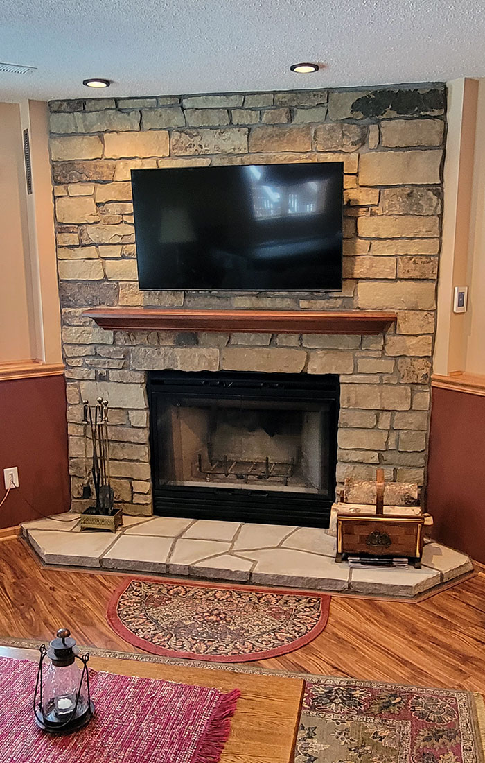 Cozy living room with a stone fireplace, mounted TV, and rustic decor, completed by Carter Custom Construction.