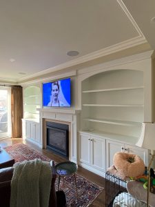 custom built white mantels, cabinetry, and shelving surrounding a gas fireplace, all built by Carter Custom Construction