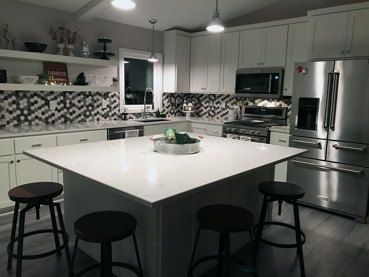 Modern kitchen with a large island, hexagonal tile backsplash, and stainless steel appliances, completed by Carter Custom Construction.