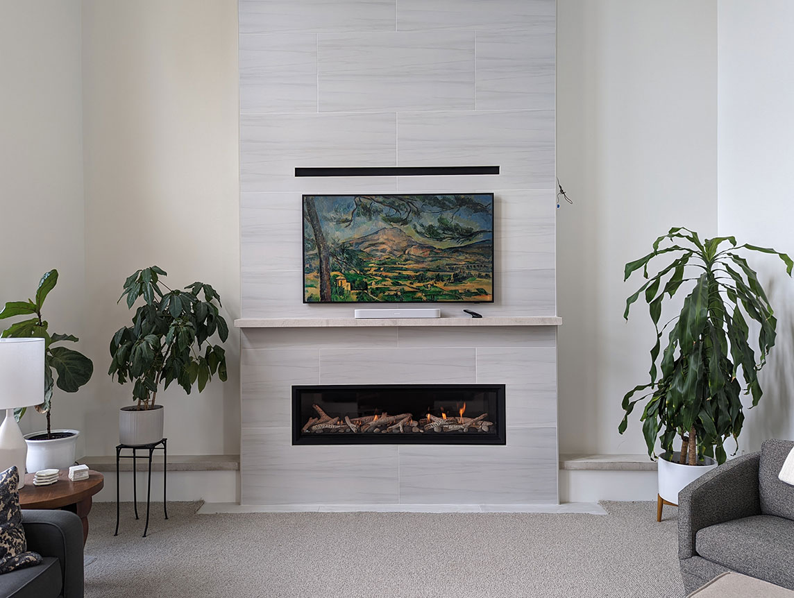 Long and narrow gas fireplace surrounded by floor to ceiling white marble with white mantels ledge