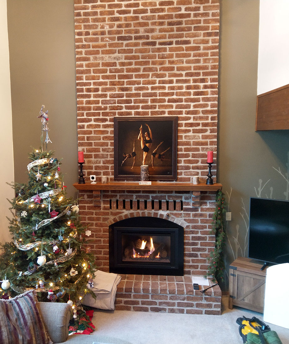 Tall, traditional brick fireplace with insert to represent the service and repair services offered by Carter Custom Construction