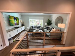main-level-custom-remodel_twin-cities Cozy living room at the top of stairs with rod-iron railing detail and the living room has a white shiplap statement wall, remodeled by Carter Custom Construction