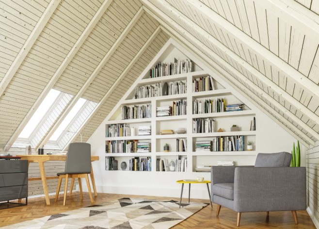 Bright, modern attic space featuring slanted wooden ceilings, built-in triangular bookshelves filled with books, a cozy seating area with a gray armchair, and a wooden desk by the window, creating an ideal reading and workspace.